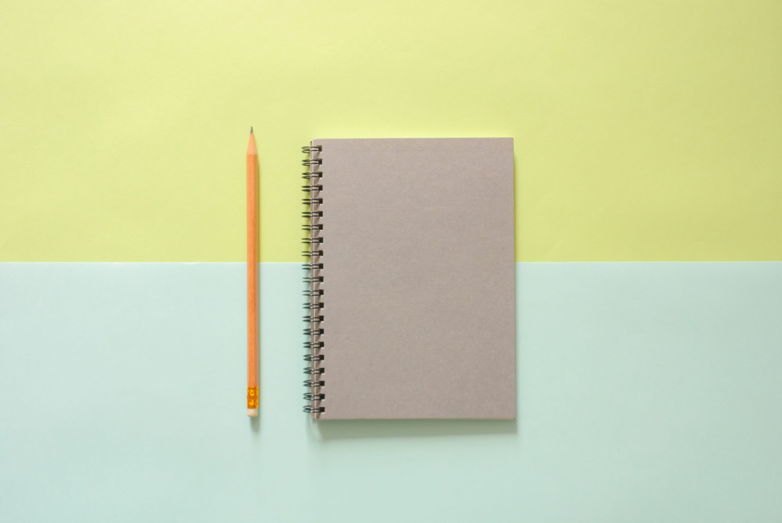 Minimal work space - Creative flat lay photo of workspace desk with sketchbook and wooden pencil on copy space green and blue pastel background. Top view , flat lay photography.